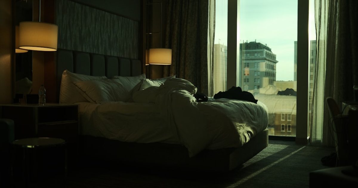 A hotel room interior with a made bed